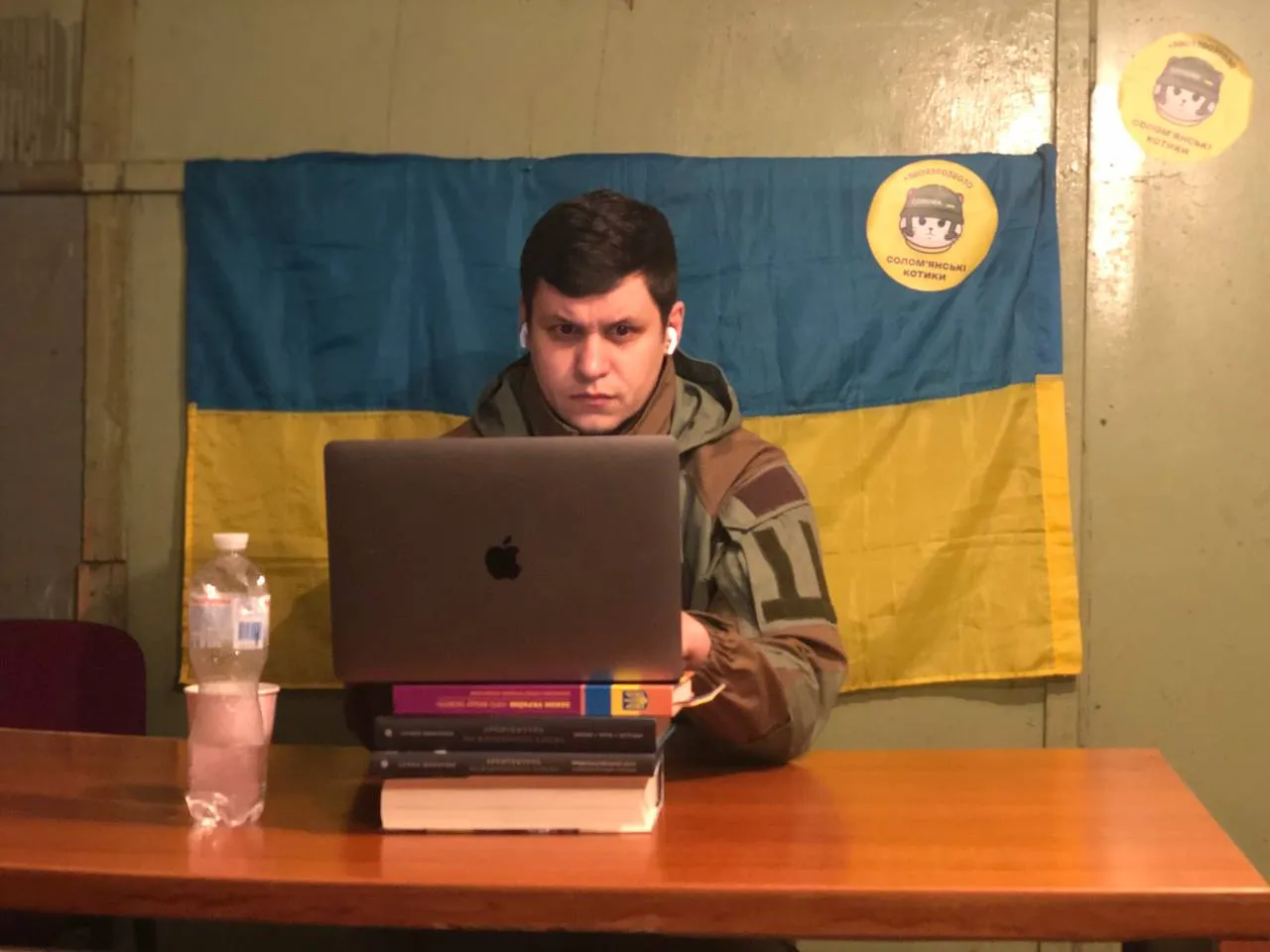Роман Грищук в подвальному приміщенні, дивиться на ноутбук, який стоїть на книжках